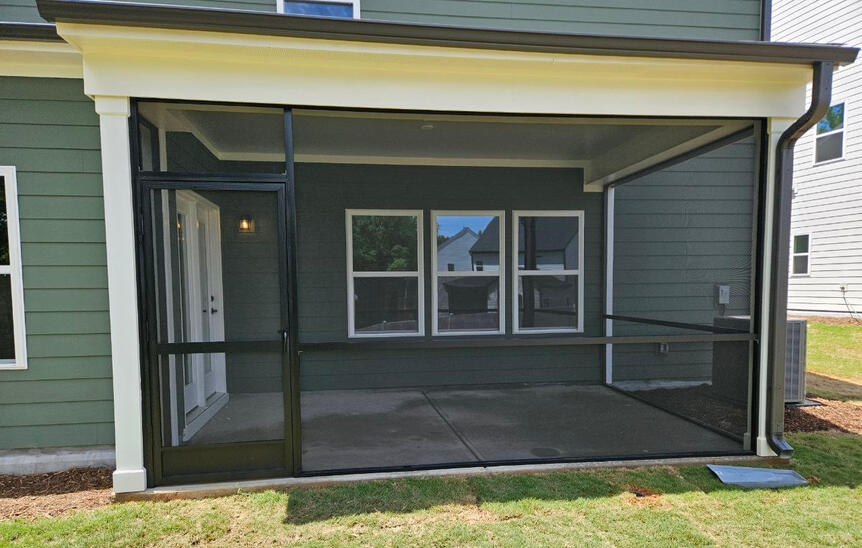 Dark framed screen room enclosure attached to a home with screened walls and covered roof. Call or text Raleigh Outdoor Spaces for a free consultation.