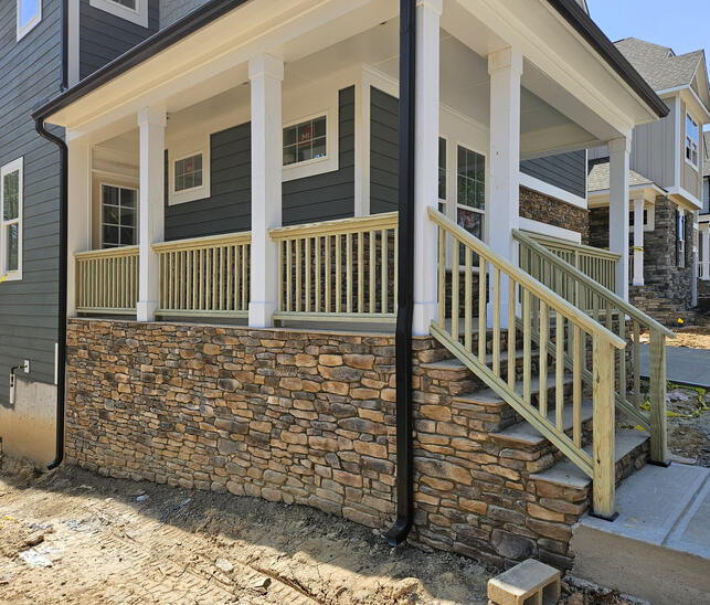Residential front porch featuring custom wood railing installation and stair rail system. Call or text Raleigh Outdoor Spaces for a free consultation.